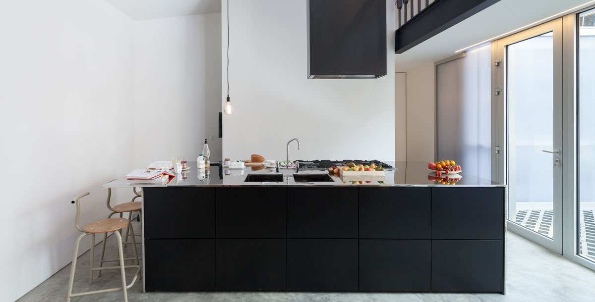 modern kitchen with black cabinets and an island extractor fan above the hob