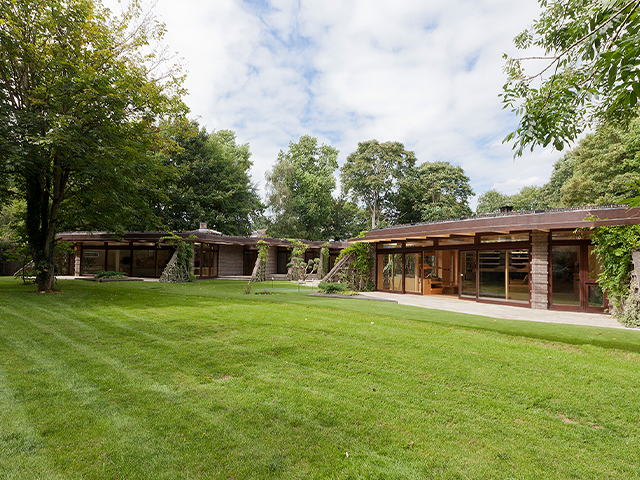 Exterior view of the Grand Designs Hertfordshire abbey project with plenty of trees and green grassland surrounding the property