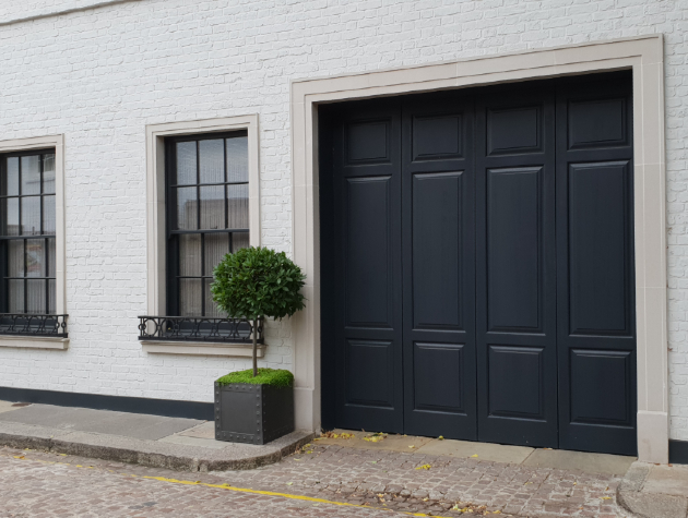 house with white painted brick and black garage door