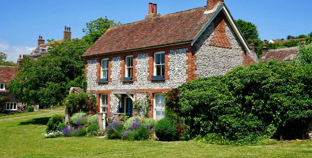 stone cottage with mature hedges and blue skies