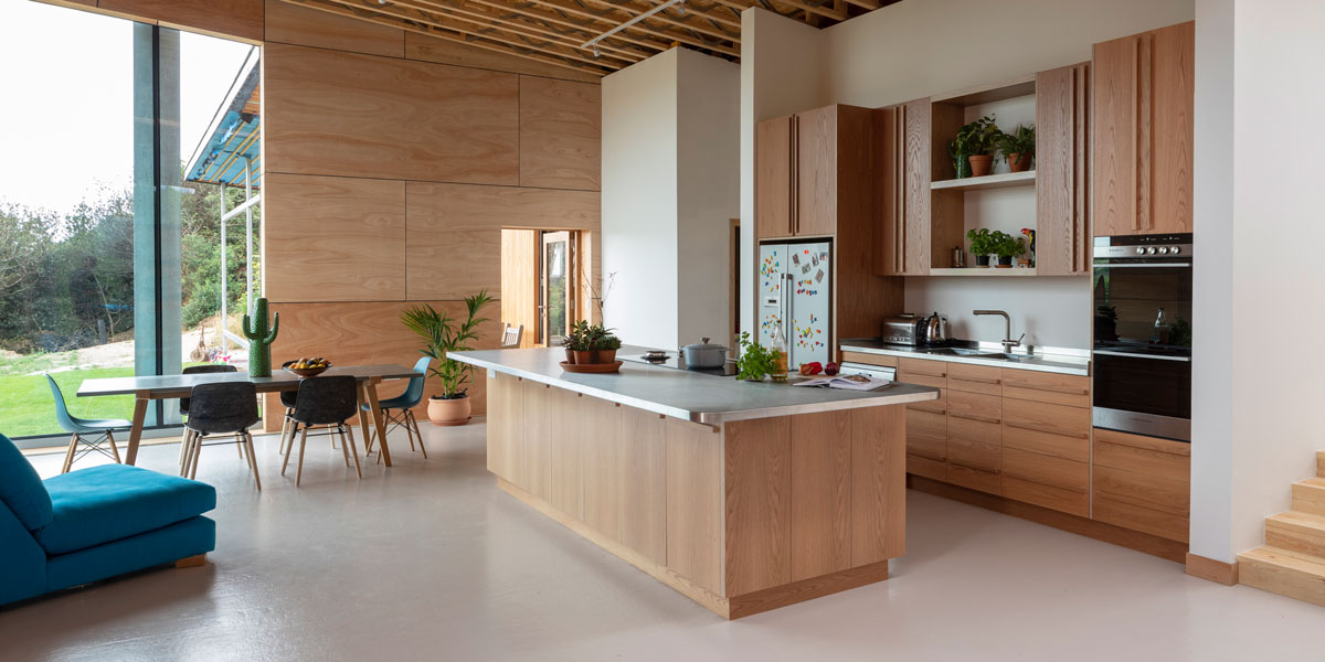 Large open plan kitchen with pale wood units and a concrete work surface