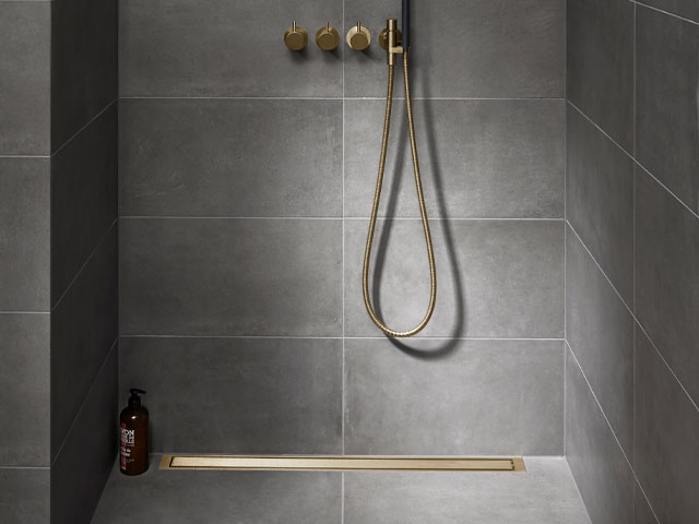 grey wet room with gold shower fixtures