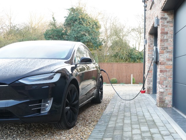 electric car connected to charging point mounted on garage