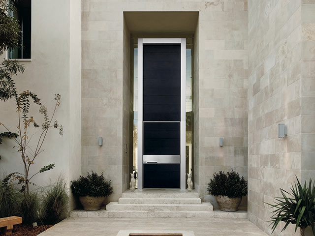 Masterpiece front door in concrete building with plants surrounding