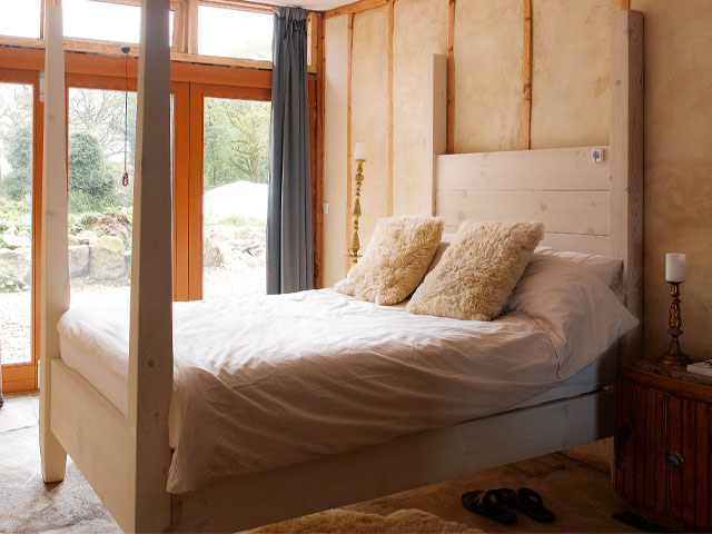 A four-poster bed in limed oak in the Grand Designs earthship house