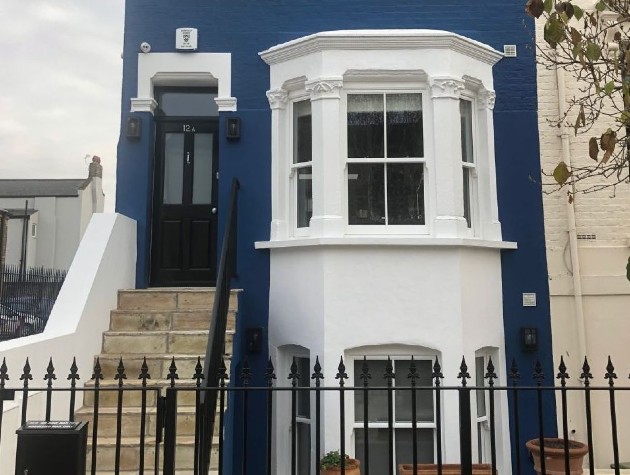 three storey home painted blue with white bay windows