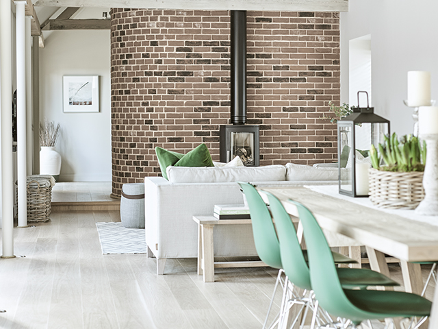 Open-plan ktichen-diner-living space with white-washed walls and floors and exposed brickwork 