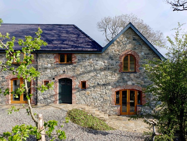 Exterior of new rustic style home in stone with period style timber windows and a slate roof by Waterhouse Architects