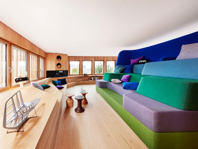 Contemporary wooden interior with colourful cushioned raised platforms inside timber framed Haussicht eco home by Baufritz