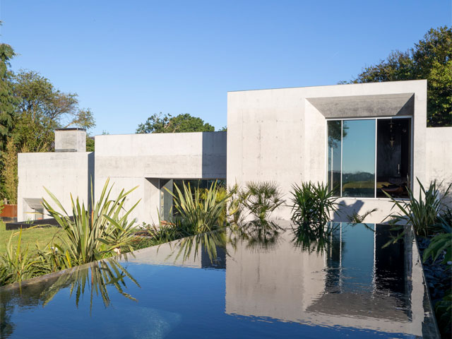 the exterior of the grand designs concrete house in east sussex with swimming pool and tropical plants
