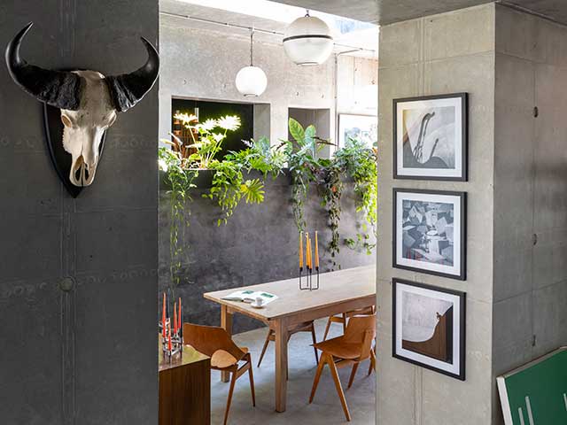 Sunken dining table in Grand Designs concrete house, surrounded by foilage and grey concrete walls