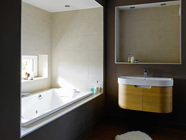 Bathroom with built in bath tub, wall hanging sink and cream and black tiles