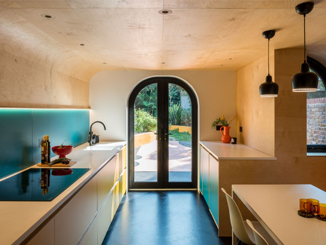 A colourful space with curved plywood and budget formica units