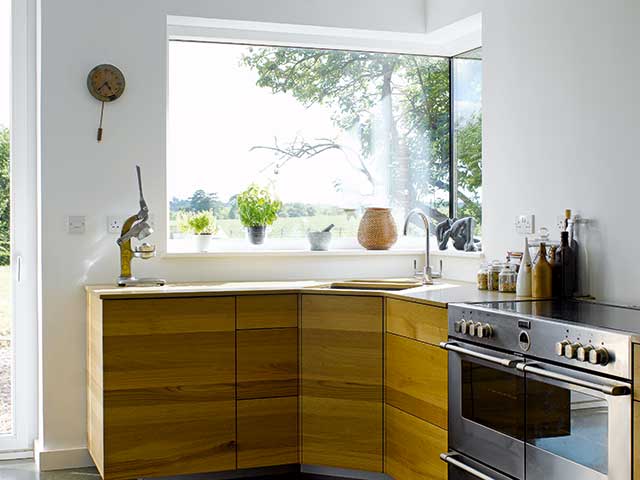 Wooden cabinets in kitchen with built in oven and window overlooking grounds