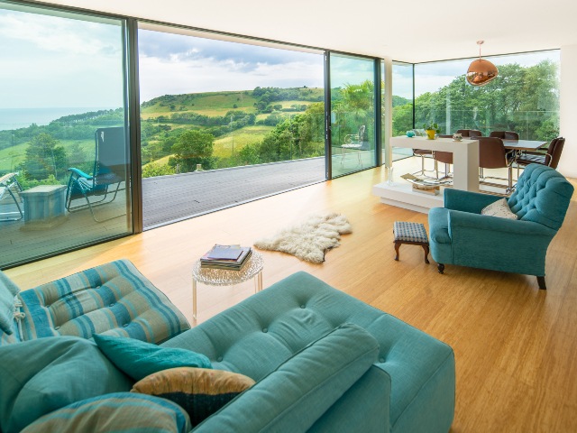 lounge and dining room with blue furniture, sliding doors opening out to porch and view of landscape