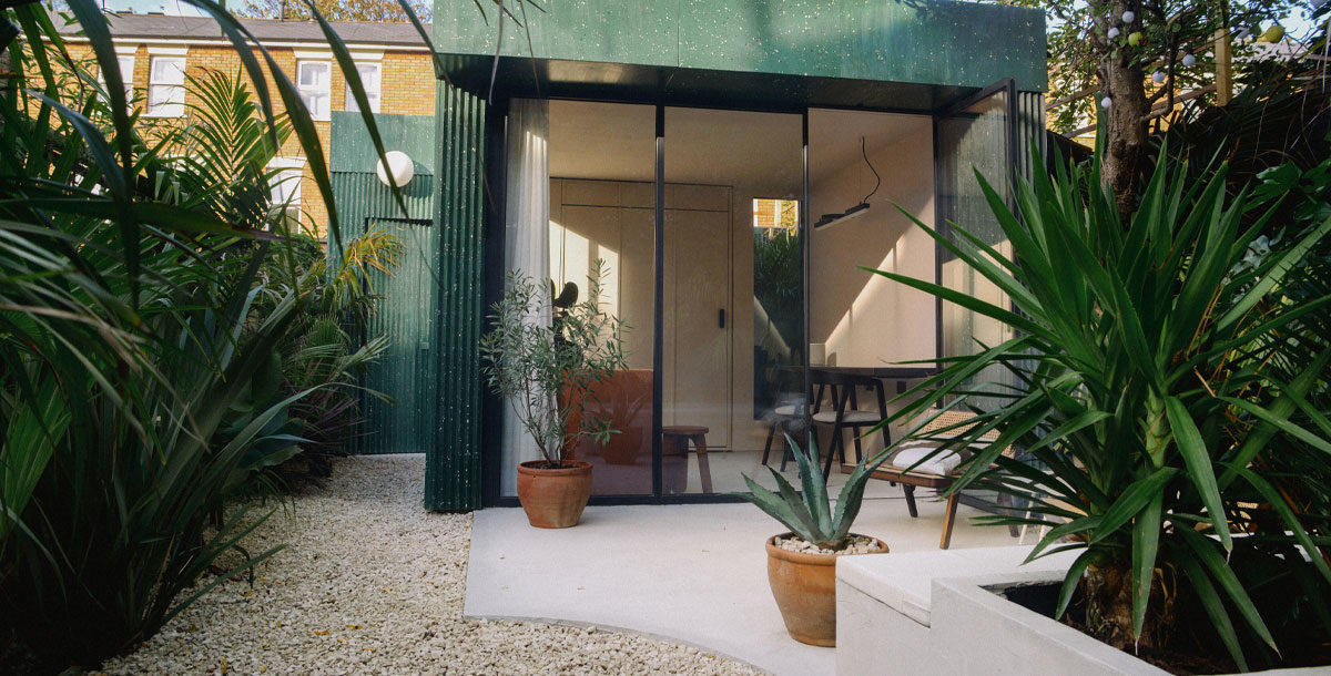 green terrazzo-clad garden studio surrounded by tropical plants in London
