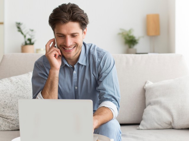 man on white sofa searching for remortgage deals on his laptop