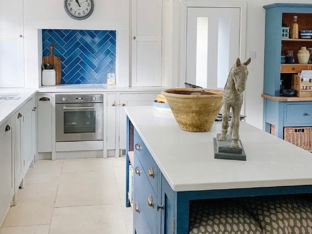 white flagstone flooring in a contemporary kitchen with white units and a blue chevron tile splashback
