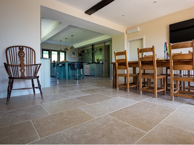 stone-effect flagstone flooring flowing through a large open-plan family kitchen dining area