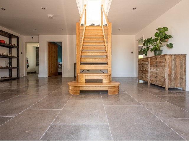 concrete effect flagstone flooring in a large hallway with bespoke timber staircase 