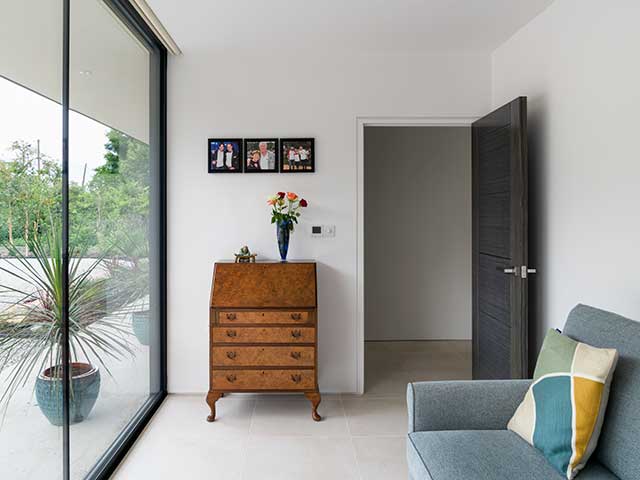 Bifold doors in chair with family photos on walls in the Grand Designs house in Ely