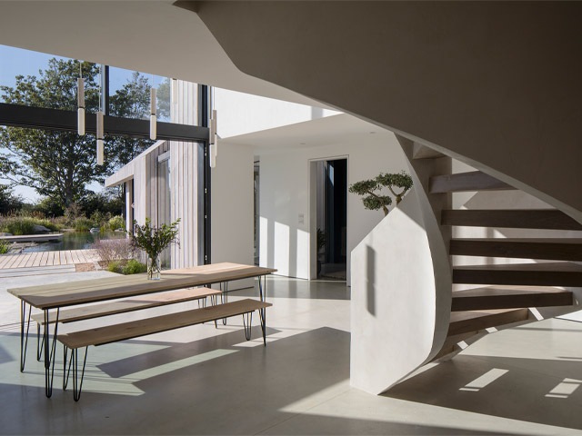 Indoor-outdoor poolside area of a modern house next to a swimming pond