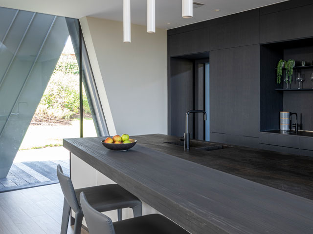 Inside the sculptural house in Devon - dark walls and a dark kitchen island contrast with white walls and lots of natural light