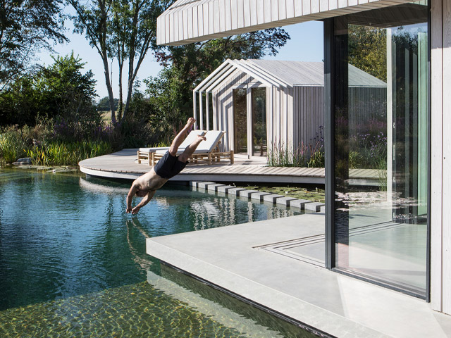 Grand Designs swimming pond house in Chichester with white timber cladding