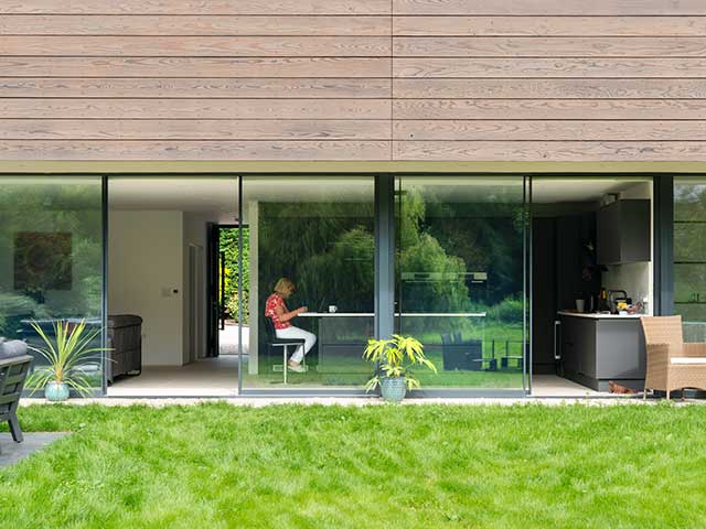 gretta in her timber clad grand designs home with floor-to-ceiling windows
