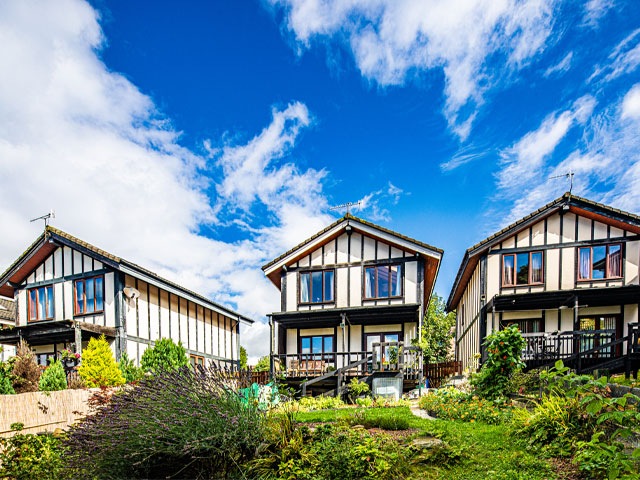 Timber-framed Walter Segal houses in Sheffield with blue skies and lots of plants