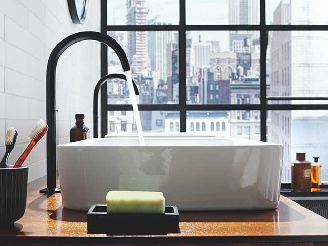 White basin with black taps in white tiled room 