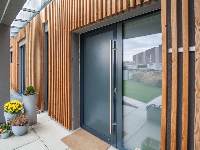 Exterior of modern property with vertical wood cladding and triple-glazed window and door entrance