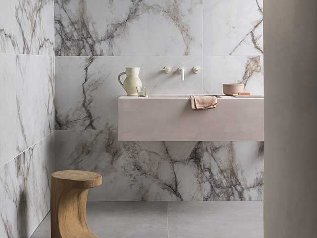 Porcelain white tiled bathroom with grey marble effect, and pink basin with built in taps