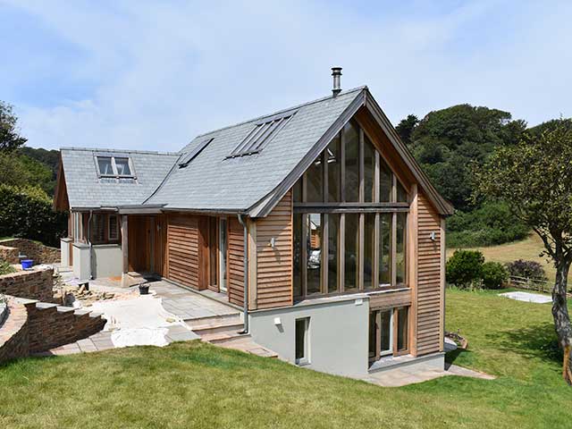 Self-build home with slated sloping roof and wooden panelled exterior on a hill