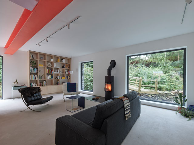 Inside the Grand Designs Cumbrian mill with red steel ceiling beam, log burner and huge picture window