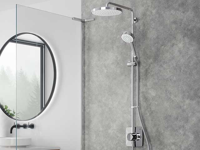 Grey marble wall behind silver rainfall shower with separate head with circular mirror to the side