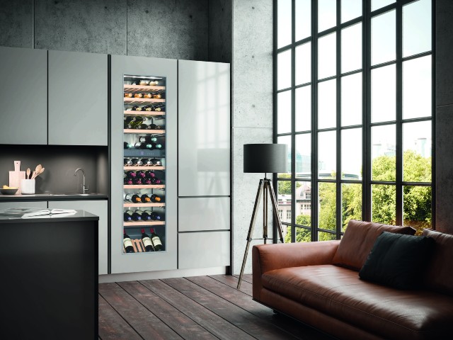 quiet wine fridge in a modern grey kitchen with island and leather sofa by a big crittall window