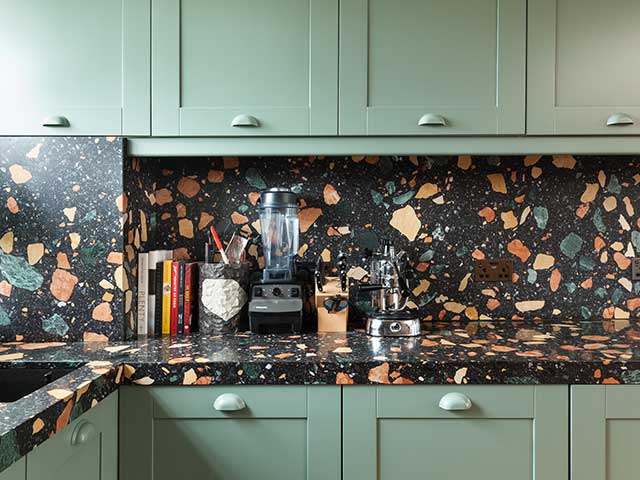 Terrazzo splashback and work surface in a modern kitchen with pale green cabinets