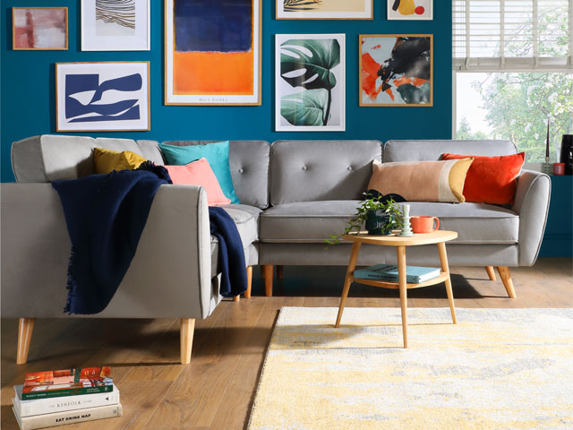 modern living room with grey furniture, blue wall, colourful wall art, wooden floor and yellow rug