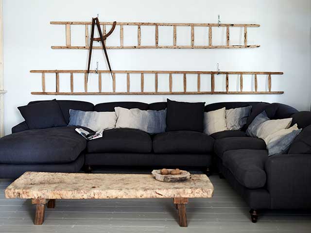 Loft corner sofa in dark with ladders mounted on wall behind