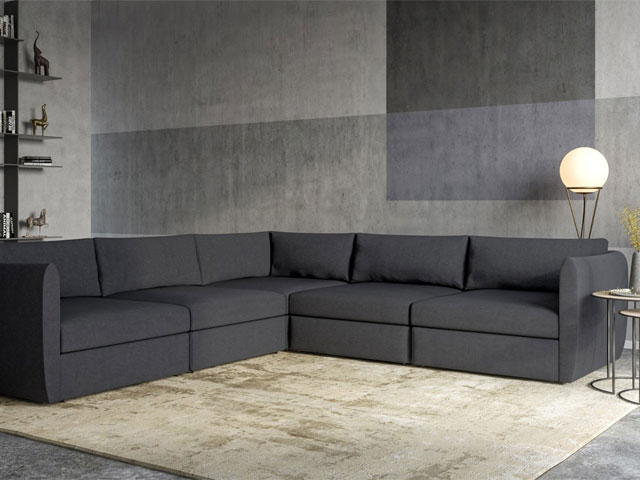 charcoal grey modular corner sofa in a modern home with large rug and textured walls