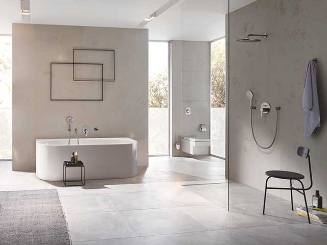 Showers and taps in bathroom with tiled flooring and marble walls
