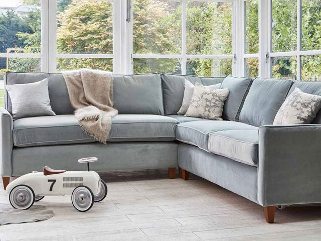 traditional style grey corner couch with wooden legs in conservatory