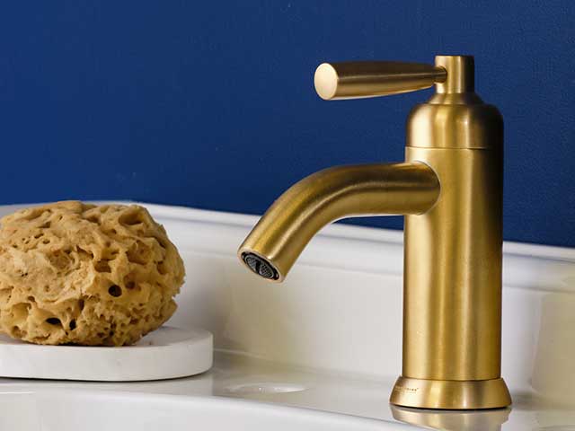 Gold tap on white porcelain sink with blue wall behind