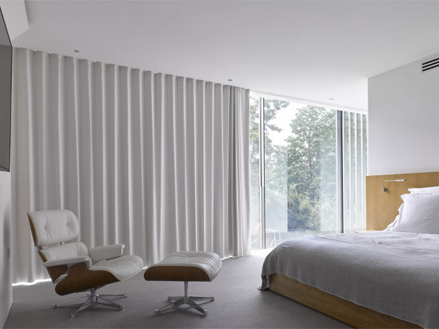 noise reducing curtains, blinds and motorised tracks in a Scandi-style bedroom with large windows