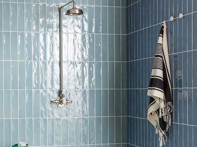 Blue tiled walls in shower with silver rainfall shower head