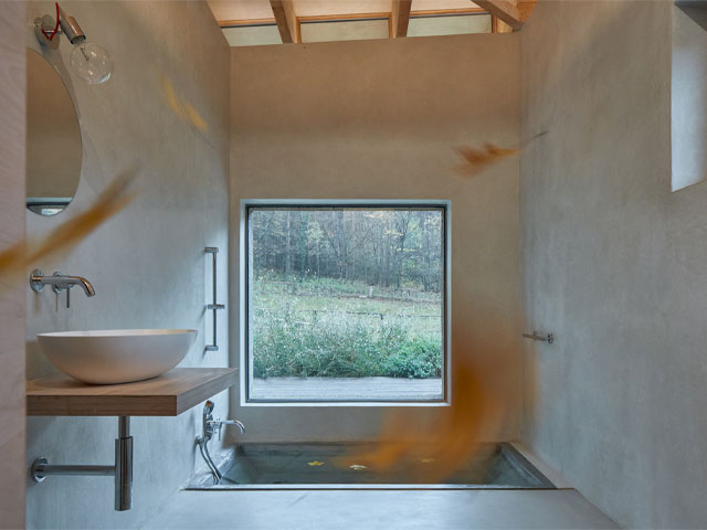 small contemporary bathroom in a hempcrete house with large picture window to the forest