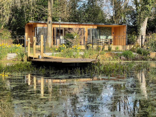 timber garden room overlooking a large pond