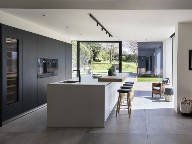 monochrome kitchen with black-grey oak cabinets and white kaolin kitchen island with cantilevered breakfast bar