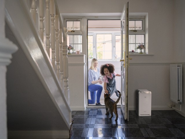 white air purifier in a large hallway where a young girl is petting a cat